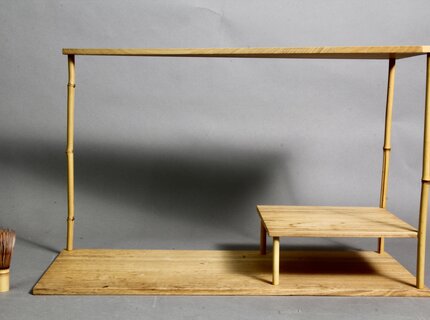 Zweistöckiges japanisches Teeregal aus hellem Holz mit Bambuspfosten und Bambusbesen als Größenvergleich Zweistöckiges japanisches Teeregal aus hellem Holz mit Bambuspfosten und Bambusbesen als Größenvergleich