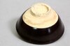 Bodenansicht einer schwarzen japanischen Teeschale Chawan mit unglasierter roher Tonfläche Bodenansicht einer schwarzen japanischen Teeschale Chawan mit unglasierter roher Tonfläche