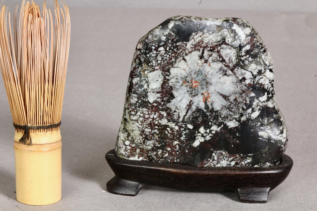 Japanischer Suiseki-Stein mit natürlichem Muster neben Chasen-Bambusbesen