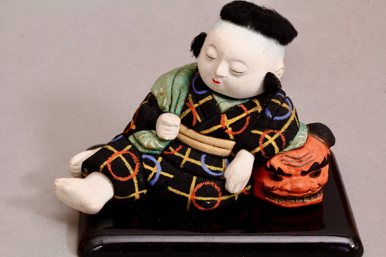Japanischer Junge schläft auf Dämonenkopf – traditionelle Figur