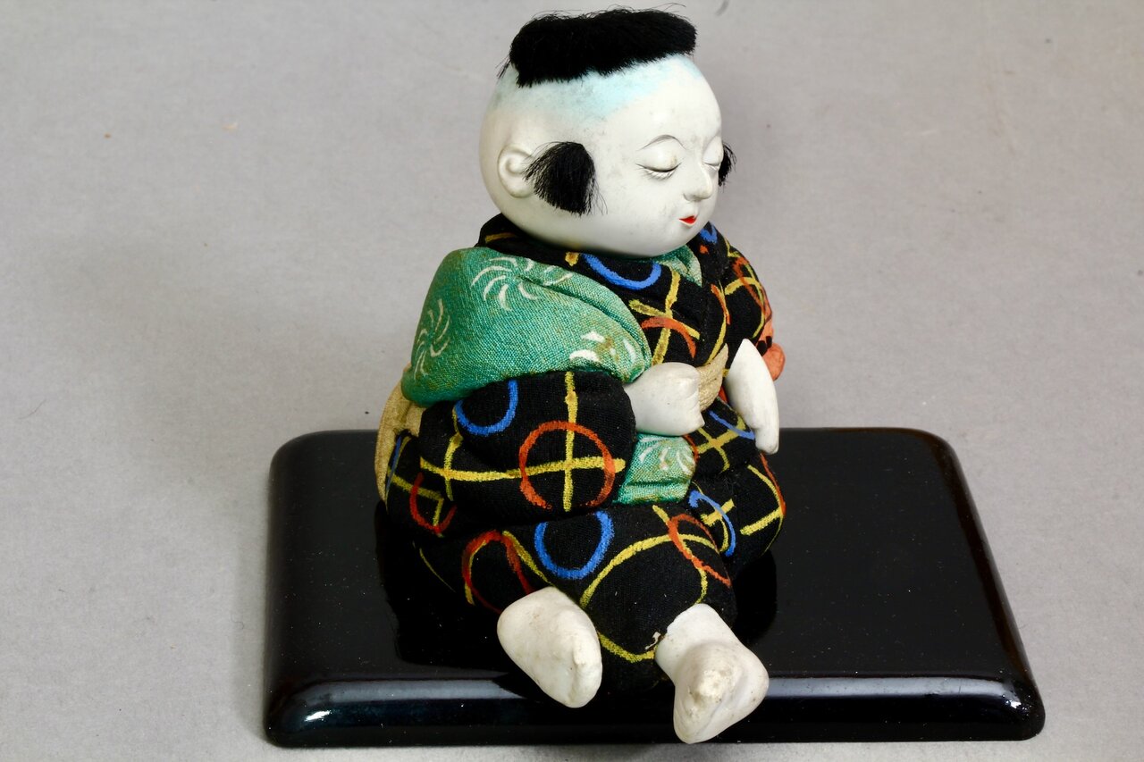 Japanische Jungenfigur in Schlafhaltung auf lackierter Basis